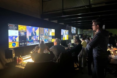 Scène éclairée avec instruments de musique, tabourets et écran affichant un logo ’ESB’ sur un fond de briques.