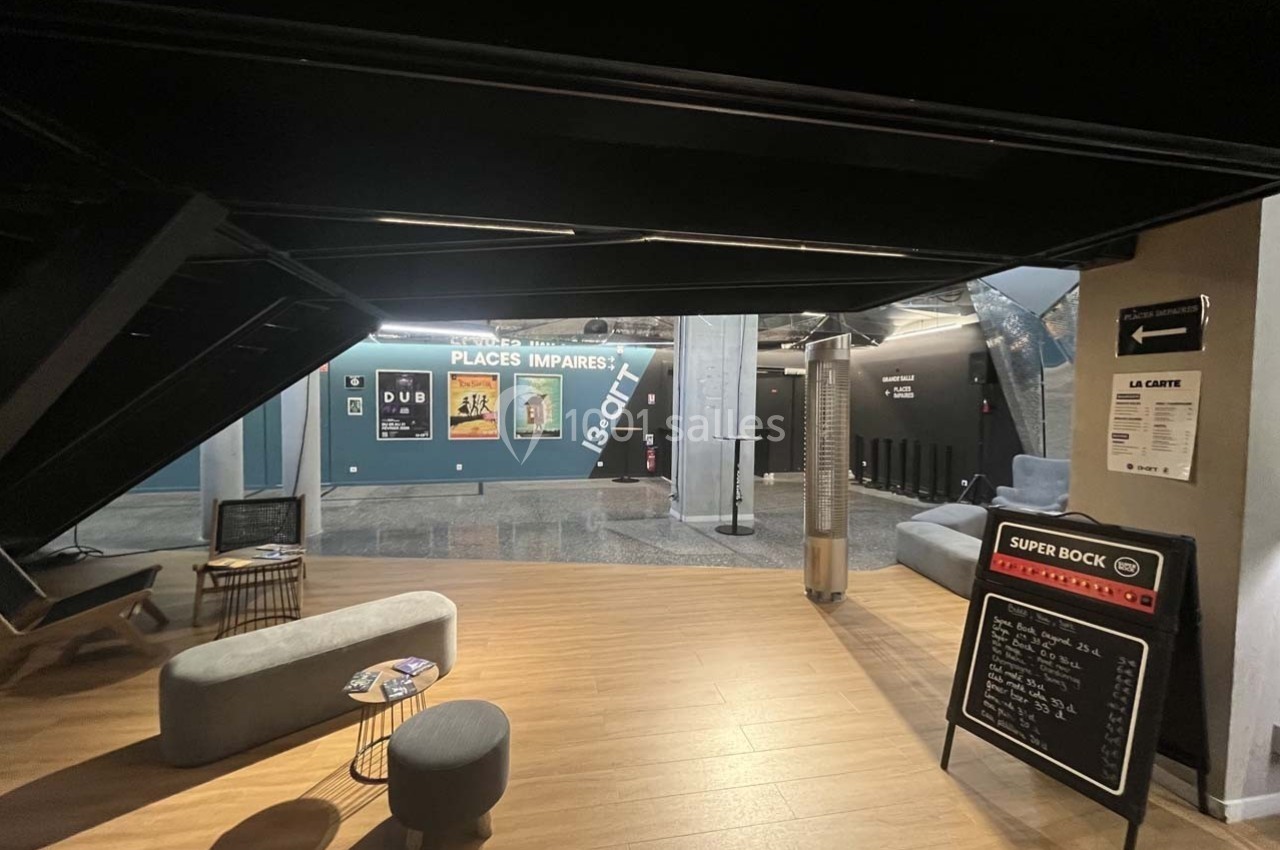 Espace d'accueil moderne avec bancs, affiches murales et tableau noir indiquant des informations.