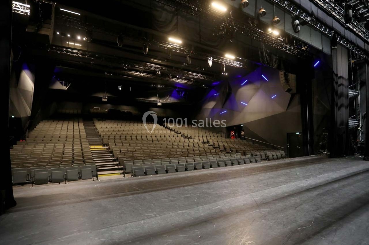Salle de spectacle vide vue depuis la scène, avec rangées de sièges et éclairage tamisé.