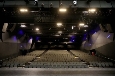 Scène éclairée avec instruments de musique, tabourets et écran affichant un logo ’ESB’ sur un fond de briques.