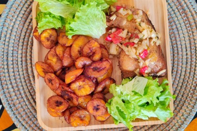 Pilons de poulet rôtis disposés sur un lit de salade verte avec une décoration en forme de rose en tomate.