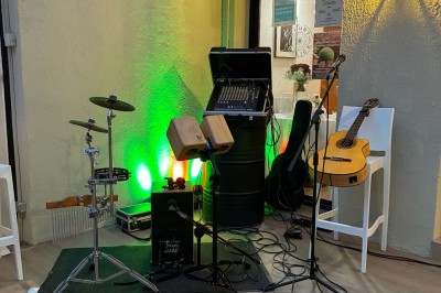 Terrasse animée d'un restaurant en soirée, avec des guirlandes lumineuses et des convives attablés sous un arbre.