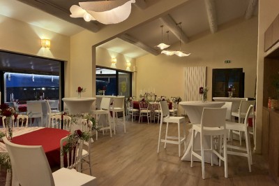 Terrasse animée d'un restaurant en soirée, avec des guirlandes lumineuses et des convives attablés sous un arbre.