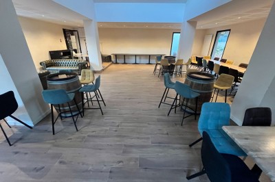 Terrasse animée d'un restaurant en soirée, avec des guirlandes lumineuses et des convives attablés sous un arbre.