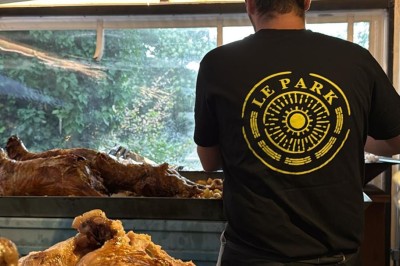Terrasse animée d'un restaurant en soirée, avec des guirlandes lumineuses et des convives attablés sous un arbre.