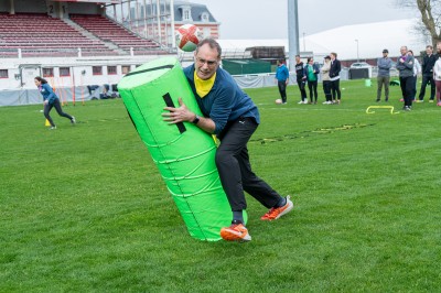 Miniature Team Building Vue d'un match de rugby dans un stade, avec un jacuzzi au premier plan et des spectateurs en tribunes.