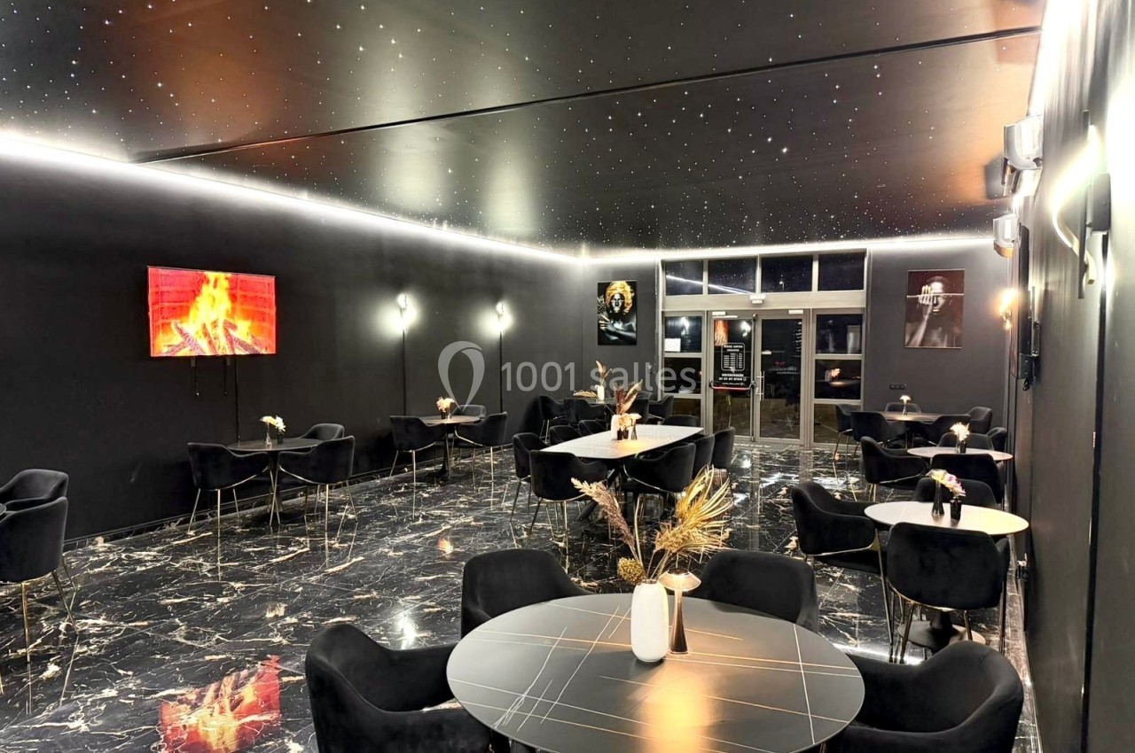 Salle moderne avec tables rondes, chaises noires, sol en marbre, plafond étoilé et décorations murales.