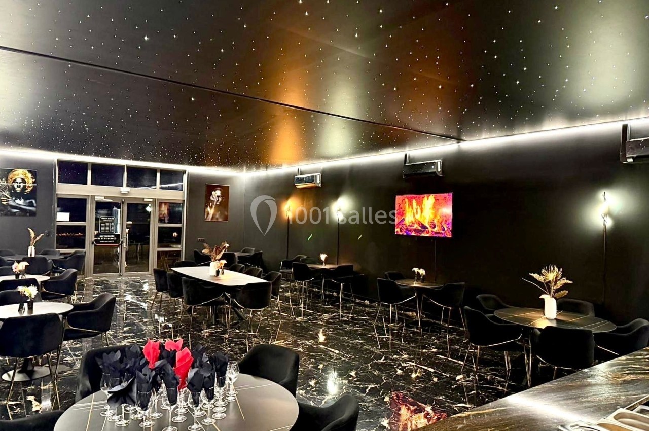 Salle de restaurant moderne avec tables noires, sol en marbre, éclairage tamisé et plafond étoilé.