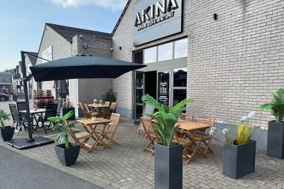 Étagères en verre avec des verres et des bouteilles d'alcool alignés dans un bar au décor sombre.