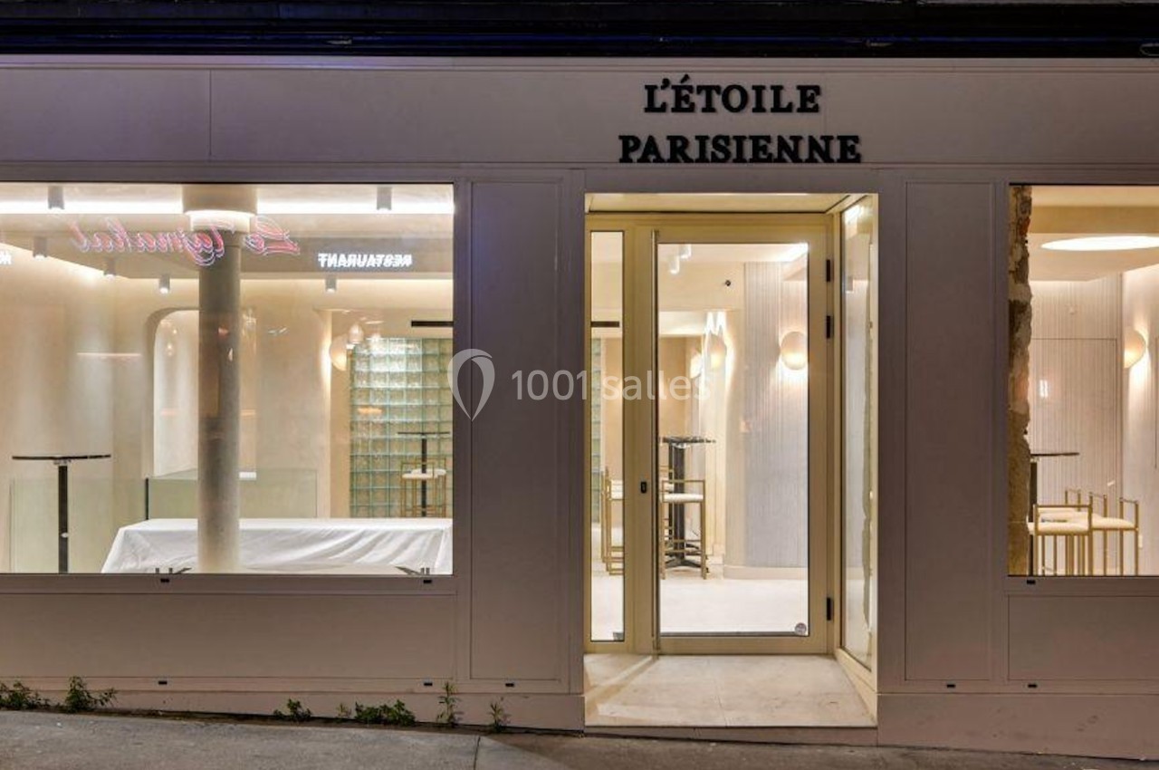 Façade d'un établissement nommé ’L'Étoile Parisienne’ avec vitrines éclairées et intérieur visible.