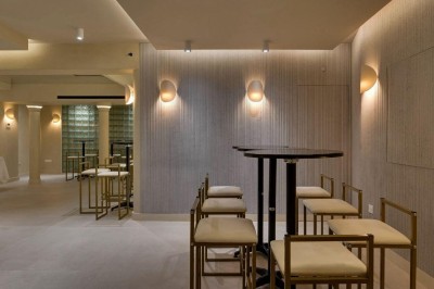 Deux lavabos en pierre avec un vase de fleurs pastel au centre, devant un miroir à double courbure.