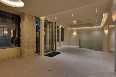 Deux lavabos en pierre avec un vase de fleurs pastel au centre, devant un miroir à double courbure.