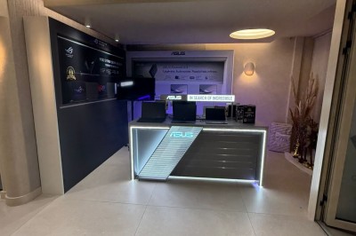 Façade d'une boutique avec vitrines éclairées, affichant des produits ASUS et un panneau ’ASUS Partner Day’.