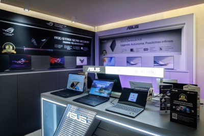 Façade d'une boutique avec vitrines éclairées, affichant des produits ASUS et un panneau ’ASUS Partner Day’.
