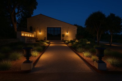 Façade d'un bâtiment en pierre avec une grande baie vitrée, entouré d'une terrasse et de végétation.