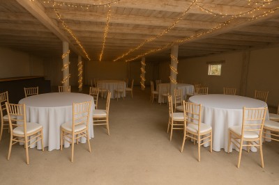 Façade d'un bâtiment en pierre avec une grande baie vitrée, entouré d'une terrasse et de végétation.