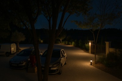 Façade d'un bâtiment en pierre avec une grande baie vitrée, entouré d'une terrasse et de végétation.