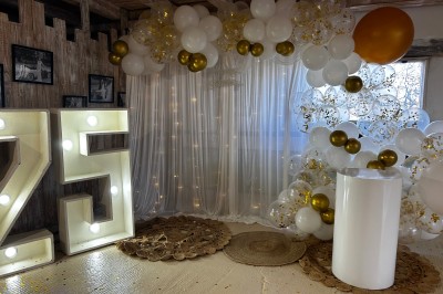 Salle de réception avec plafond en bois, décorations lumineuses et chiffre ’25’ illuminé en arrière-plan.