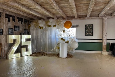 Salle de réception avec plafond en bois, décorations lumineuses et chiffre ’25’ illuminé en arrière-plan.