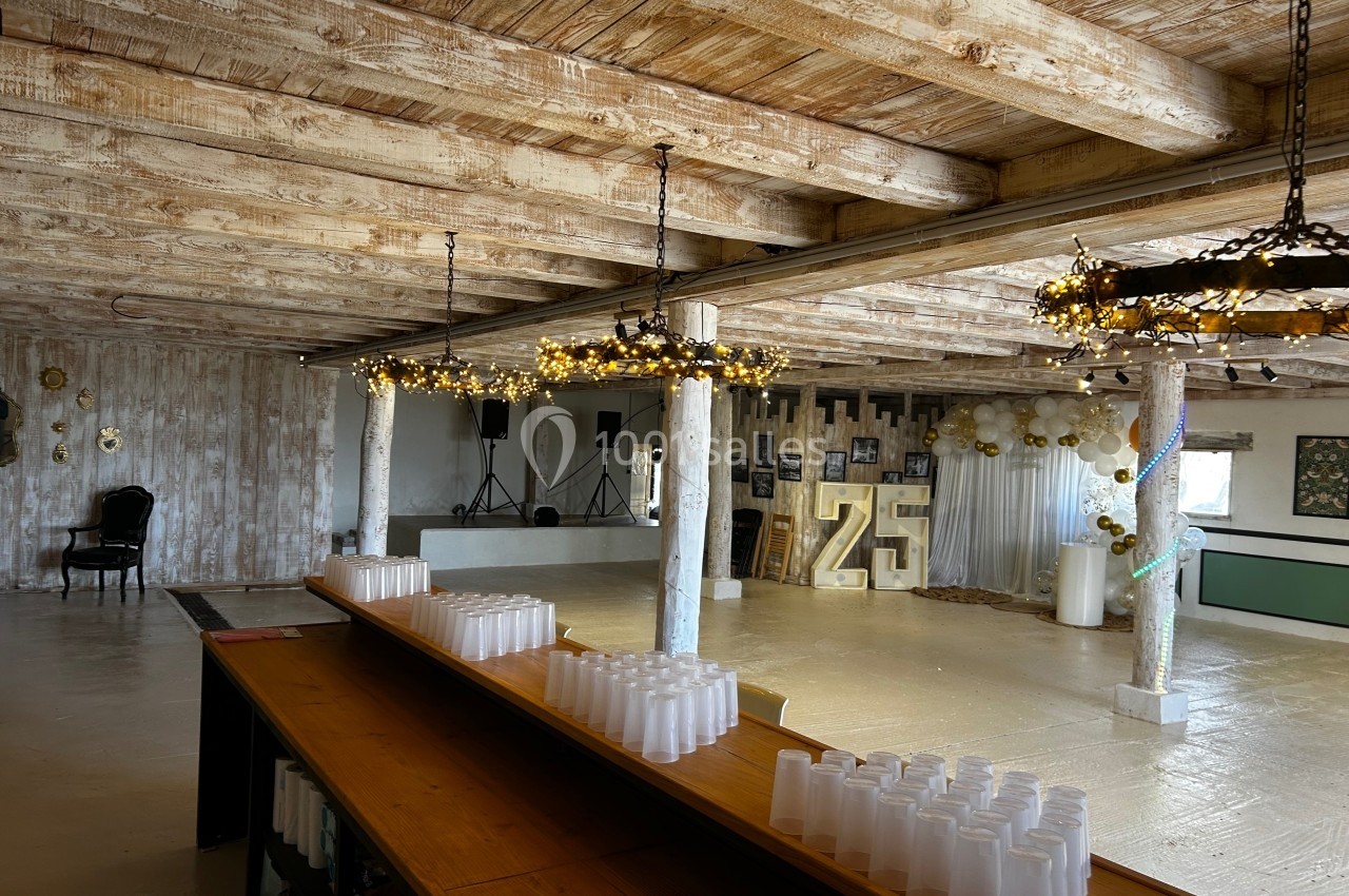 Salle de réception avec plafond en bois, décorations lumineuses et chiffre ’25’ illuminé en arrière-plan.