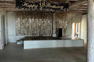 Bannière ’Happy 18th Birthday’ suspendue dans une pièce avec plafond en bois et décorations dorées scintillantes.