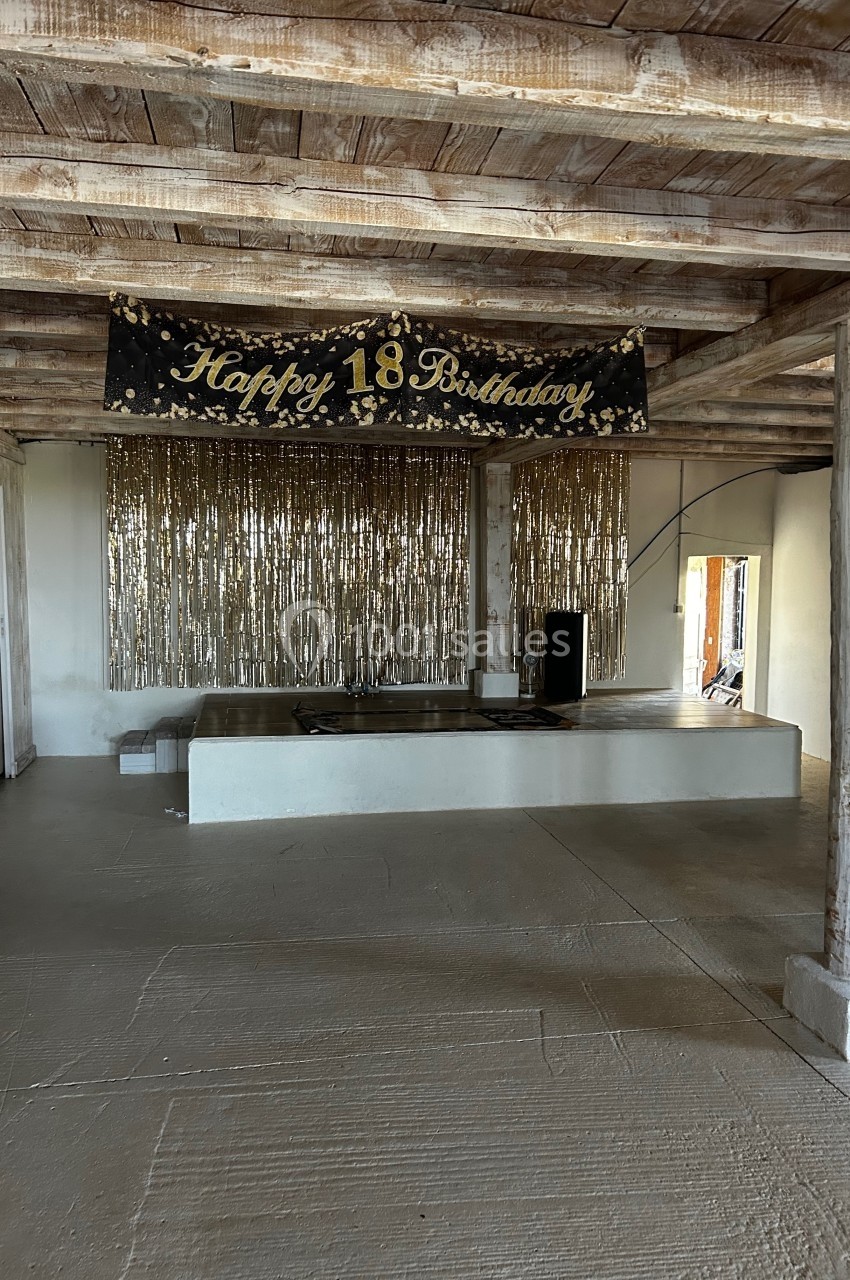 Bannière ’Happy 18th Birthday’ suspendue dans une pièce avec plafond en bois et décorations dorées scintillantes.