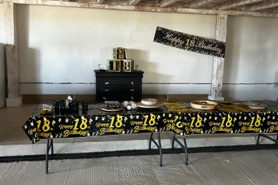 Bannière ’Happy 18th Birthday’ suspendue dans une pièce avec plafond en bois et décorations dorées scintillantes.