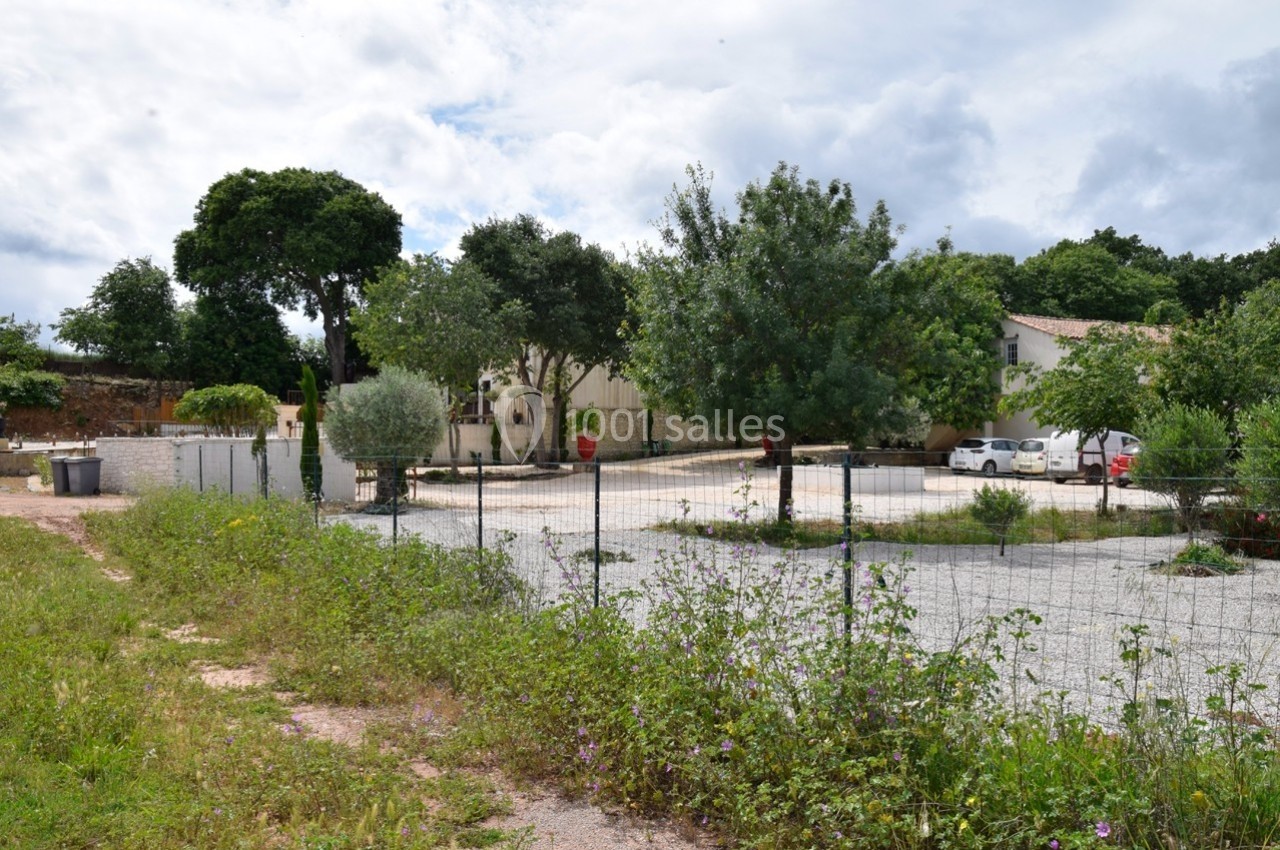 Cour extérieure avec gravier, clôture en premier plan, arbres et bâtiments résidentiels en arrière-plan.