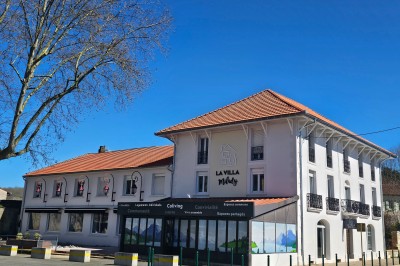 Façade d'un bâtiment moderne avec toit en tuiles rouges, balcons en fer forgé et enseigne ’La Villa Milady’.