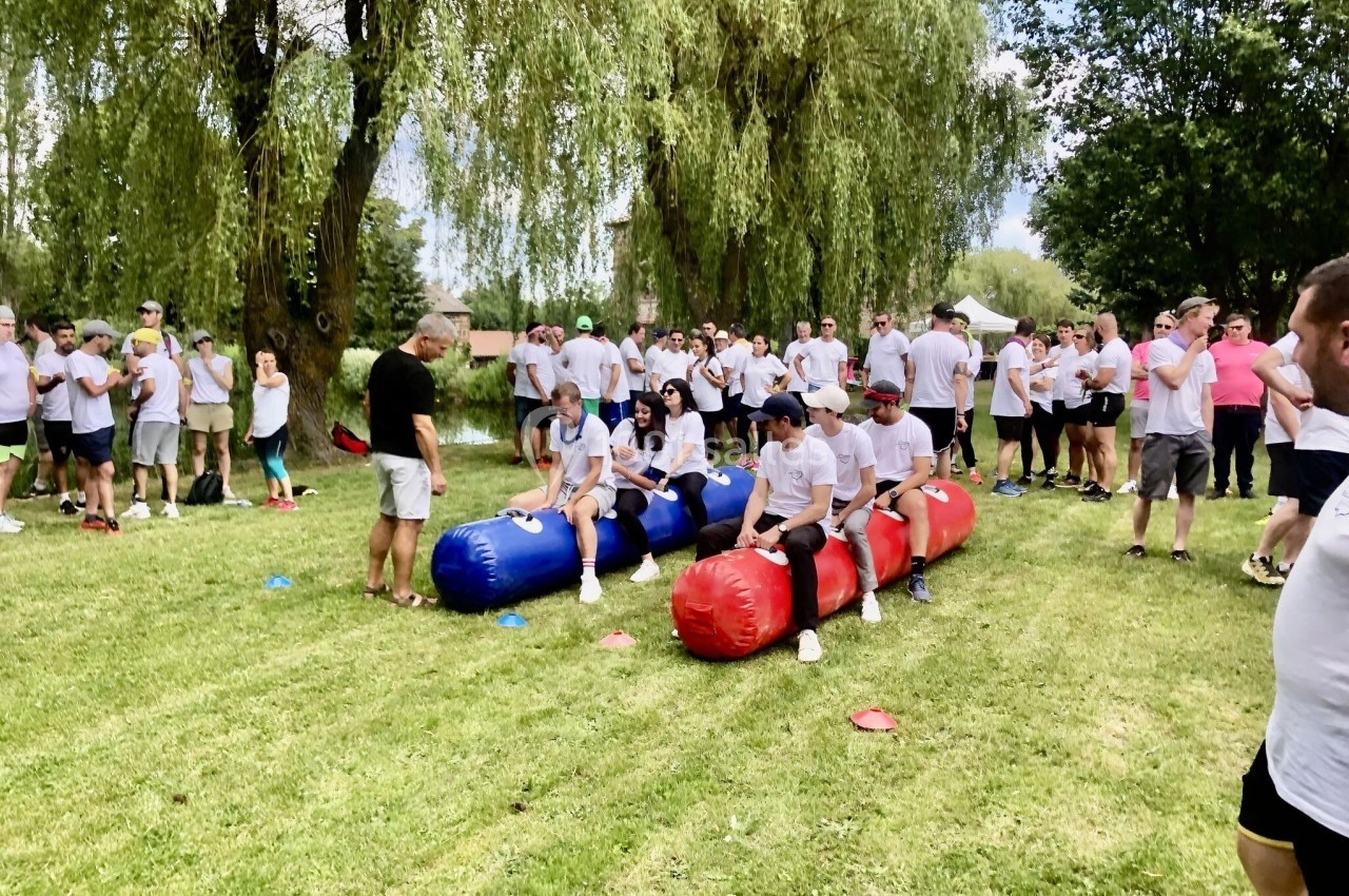 Des personnes participent à une activité d'équipe en extérieur, assises sur des structures gonflables colorées sur une…
