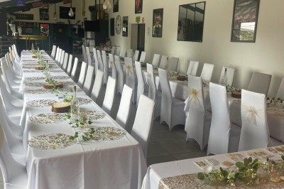 Maison moderne éclairée la nuit, entourée d'un jardin avec des arbustes et des fleurs.