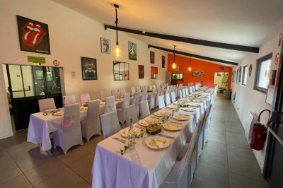 Maison moderne éclairée la nuit, entourée d'un jardin avec des arbustes et des fleurs.