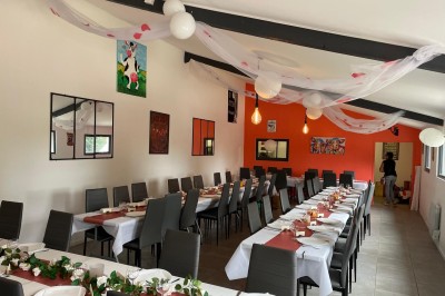 Maison moderne éclairée la nuit, entourée d'un jardin avec des arbustes et des fleurs.