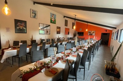 Maison moderne éclairée la nuit, entourée d'un jardin avec des arbustes et des fleurs.