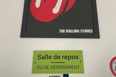 Maison moderne éclairée la nuit, entourée d'un jardin avec des arbustes et des fleurs.