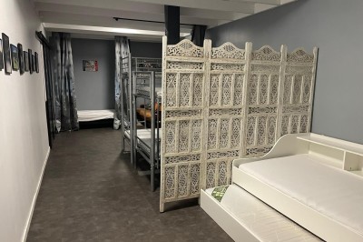 Maison moderne éclairée la nuit, entourée d'un jardin avec des arbustes et des fleurs.