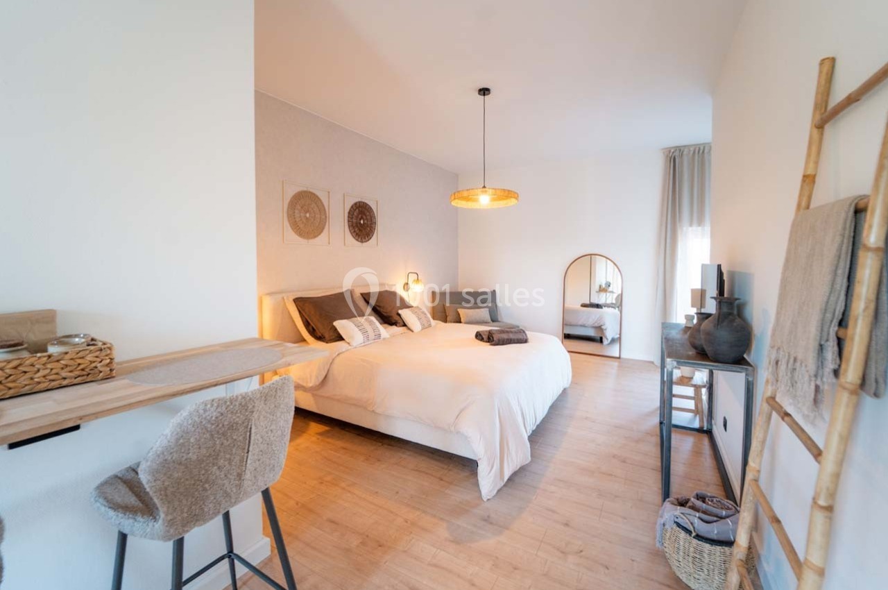 Chambre lumineuse avec lit double, décoration naturelle, miroir, bureau en bois et chaise rembourrée.