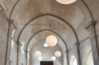 Cuisine professionnelle avec plans de travail en inox, évier, étagères et deux grandes portes de chambre froide.