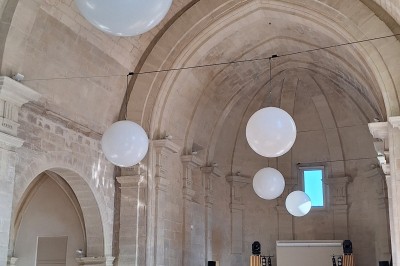 Cuisine professionnelle avec plans de travail en inox, évier, étagères et deux grandes portes de chambre froide.