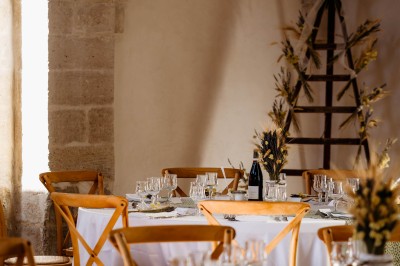 Chambre lumineuse avec lit double, bureau, fauteuils en bois, lampes et fenêtre donnant sur un paysage extérieur.
