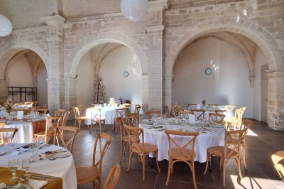 Chambre lumineuse avec lit double, bureau, fauteuils en bois, lampes et fenêtre donnant sur un paysage extérieur.