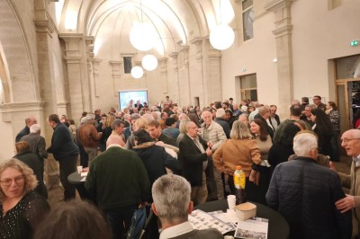 Chambre lumineuse avec lit double, bureau, fauteuils en bois, lampes et fenêtre donnant sur un paysage extérieur.