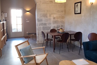 Chambre lumineuse avec lit double, bureau, fauteuils en bois, lampes et fenêtre donnant sur un paysage extérieur.