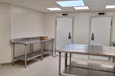 Chambre lumineuse avec lit double, bureau, fauteuils en bois, lampes et fenêtre donnant sur un paysage extérieur.