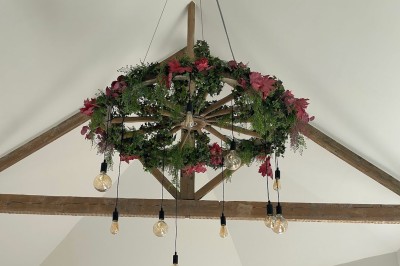 Jardin aménagé avec pelouse, terrasse en pavés, tables hautes et pergola, entouré de bâtiments en briques.