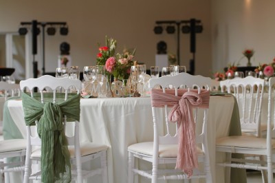 Miniature Location salle Comines-Warneton (Hainaut) - Salle de l'Arrière Boutique #8 Salle décorée pour un événement avec des chaises blanches ornées de nœuds en tissu rose et vert autour d'une table dressée.