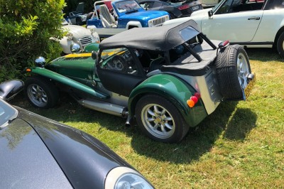 Château en briques rouges entouré de pelouses et d'arbres, sous un ciel clair et ensoleillé.