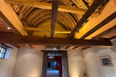 Château en briques rouges entouré de pelouses et d'arbres, sous un ciel clair et ensoleillé.