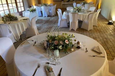 Château en briques rouges entouré de pelouses et d'arbres, sous un ciel clair et ensoleillé.