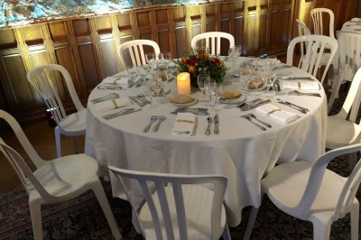 Château en briques rouges entouré de pelouses et d'arbres, sous un ciel clair et ensoleillé.